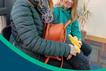 Picture of the front of the report. It contains a woman and her child sitting in a doctors waiting room smiling at the camera. The words read 'Enter and View - GP Surgeries 2023, Overall findings'